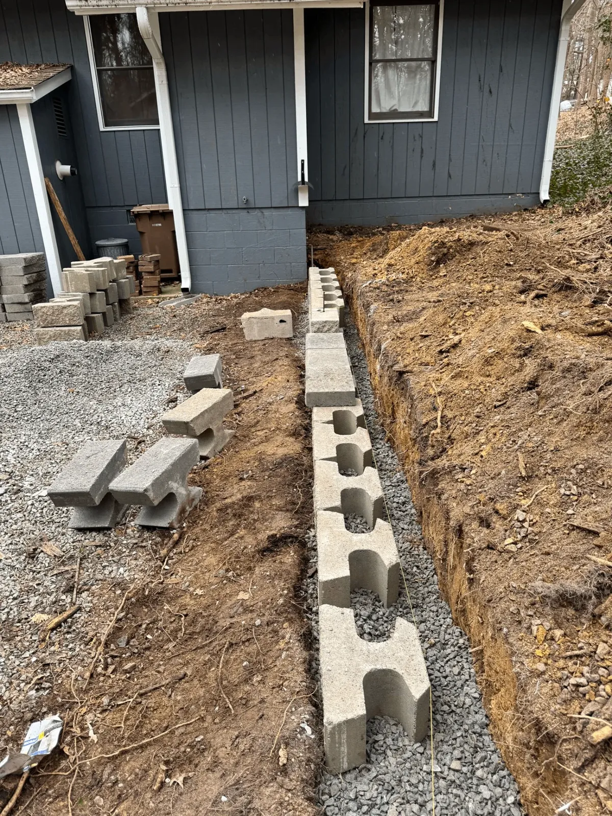 Drainage system installation for retaining wall