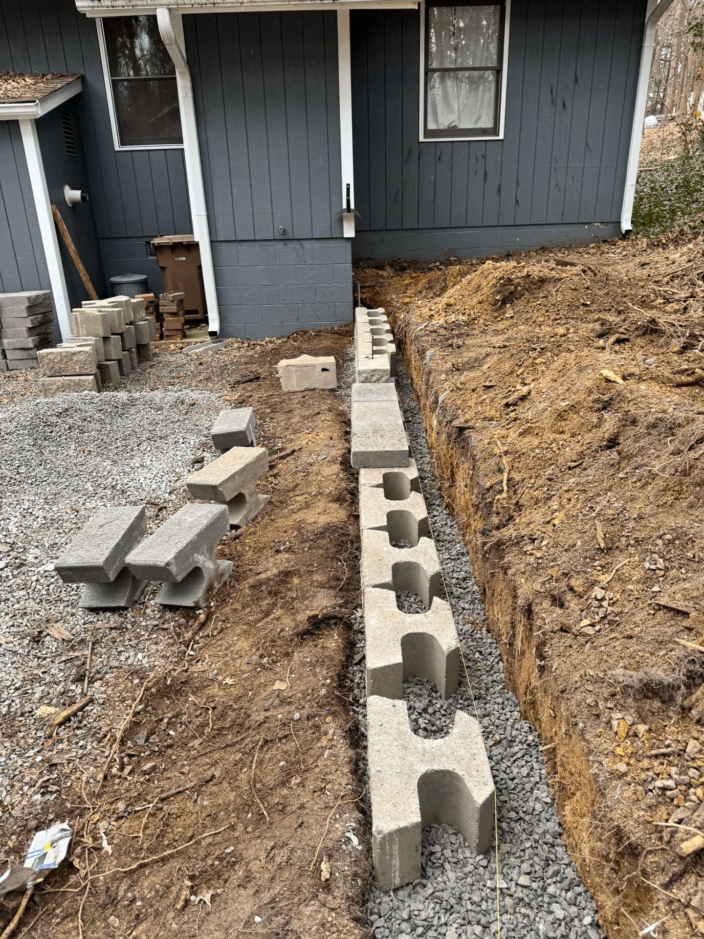 Drainage system installation for retaining wall